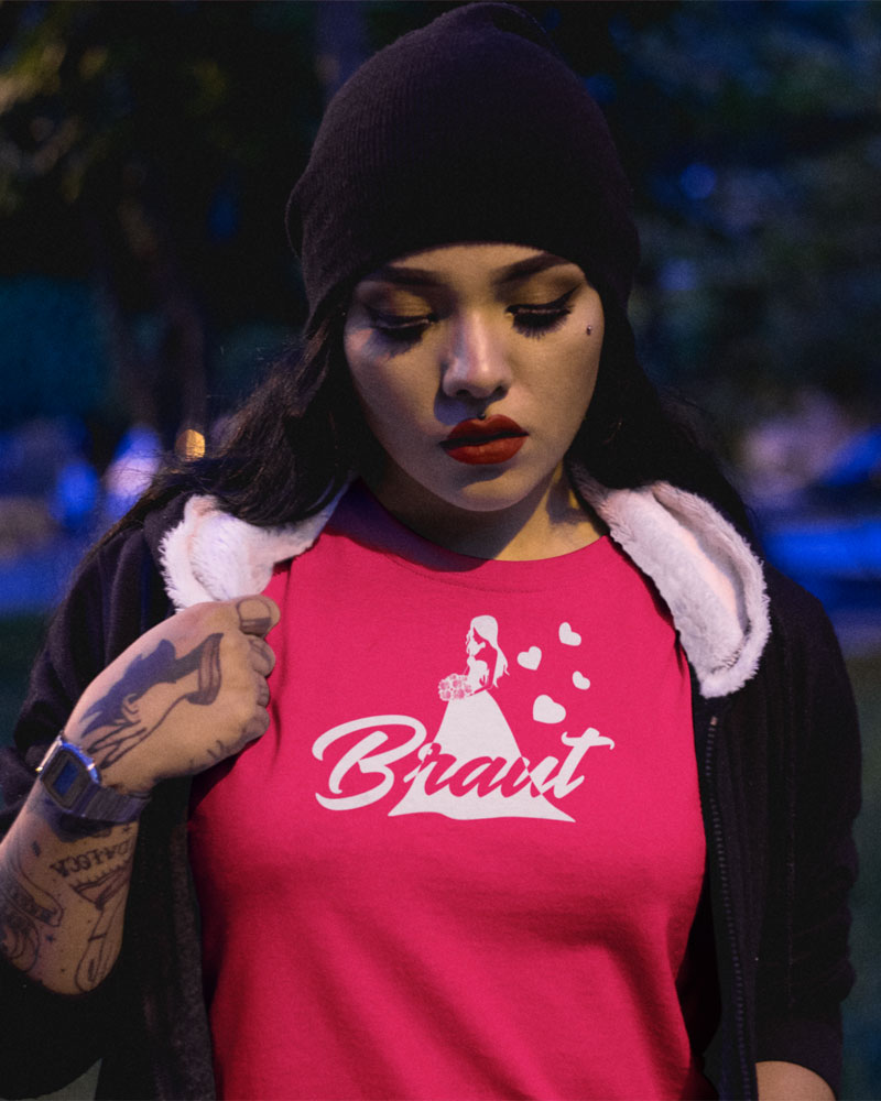 Frau trägt fuchsiafarbenes JGA-Shirt T72 mit weißer Brautsilhouette, Herzen und Schriftzug "Braut"