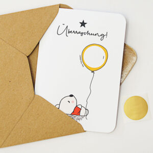 Rubbelkarte mit einem Bär, der einen Luftballon (mit beschreibbarem Rubbelfeld) hält und der Überschrift "Überraschung"