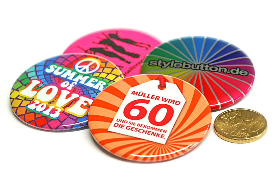 4 Stück 56-mm Buttons im Vergleich zu einer 50 Cent Münze